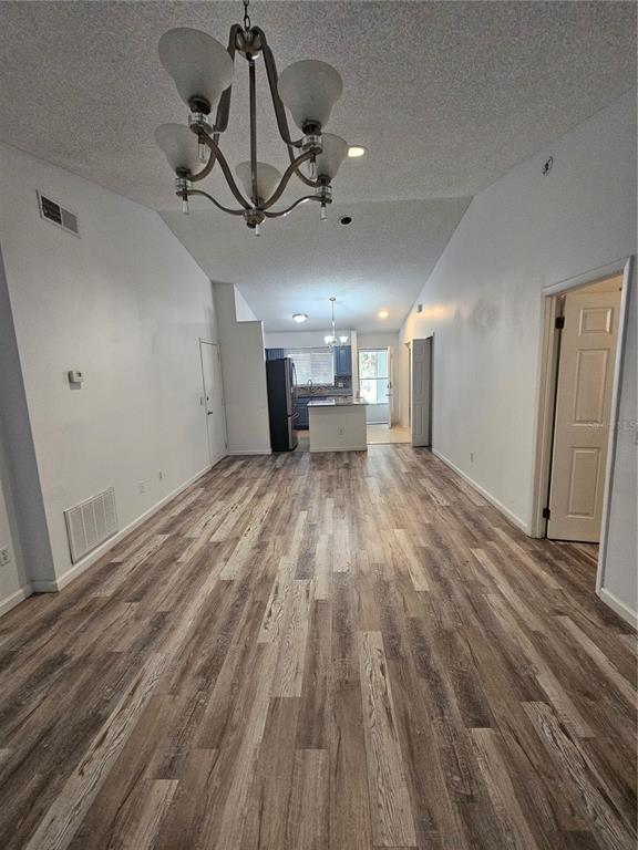 A long, open-concept living area features wood-look flooring, a vaulted ceiling, and a chandelier — 247 GROVE STREET, ORLANDO, FL