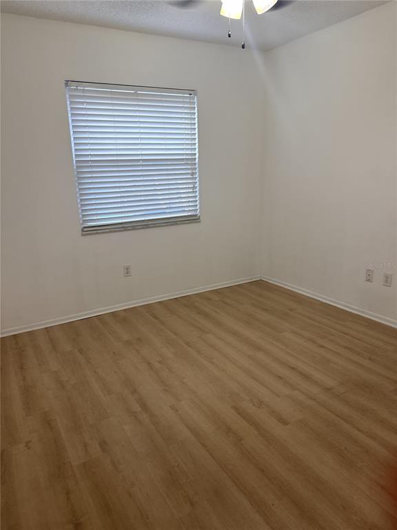 An empty bedroom features light wood-look flooring, white walls, and a window with closed blinds — 247 GROVE STREET, ORLANDO, FL