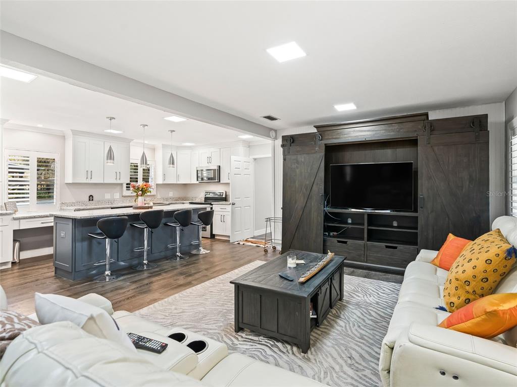 An open-concept living room features a dark wood entertainment center and a kitchen with island — 3505 NE 97TH STREET ROAD, ANTHONY, FL