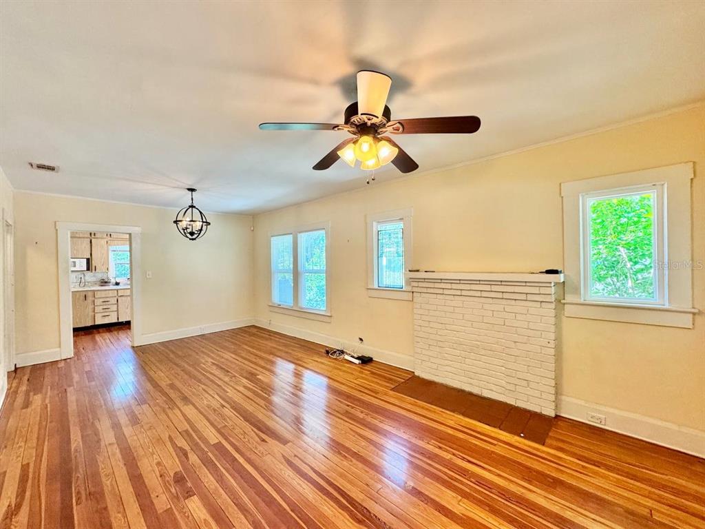 A living room features hardwood floors, a white brick fireplace, and a ceiling fan — 1215 E MOHAWK AVENUE, TAMPA, FL