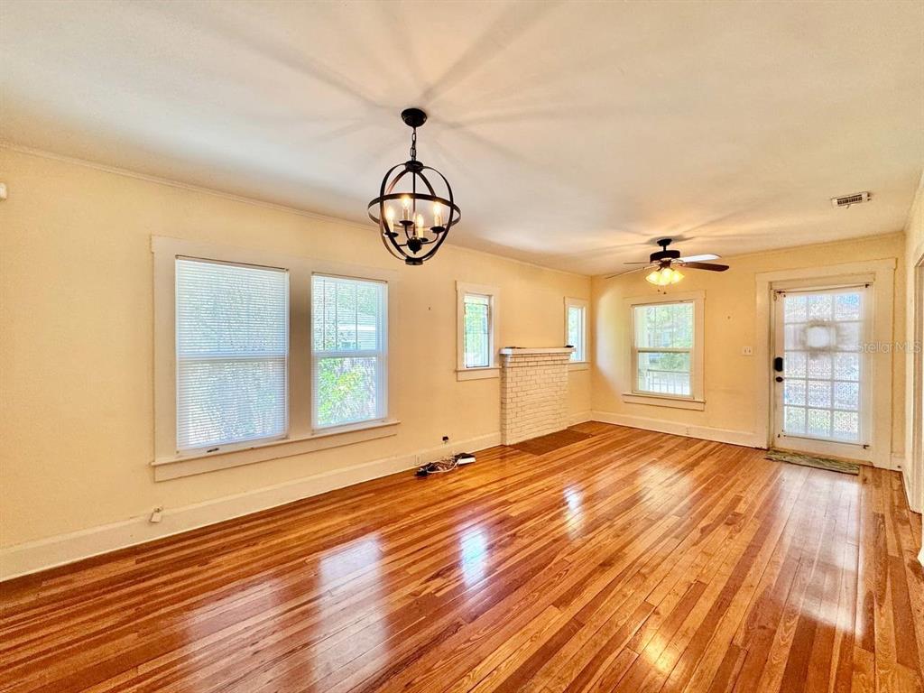 A living room features hardwood floors, a white brick fireplace, and a black orb chandelier — 1215 E MOHAWK AVENUE, TAMPA, FL
