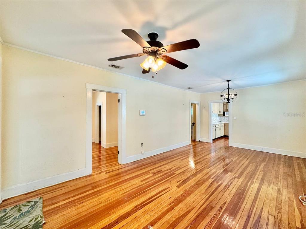 A living room with hardwood floors, a ceiling fan, and doorways leading to other rooms — 1215 E MOHAWK AVENUE, TAMPA, FL