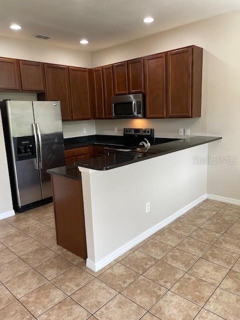 A kitchen features dark wood cabinets, stainless steel appliances, and a black granite breakfast bar — 3809 BLACK SPRUCE LANE, WINTER SPRINGS, FL