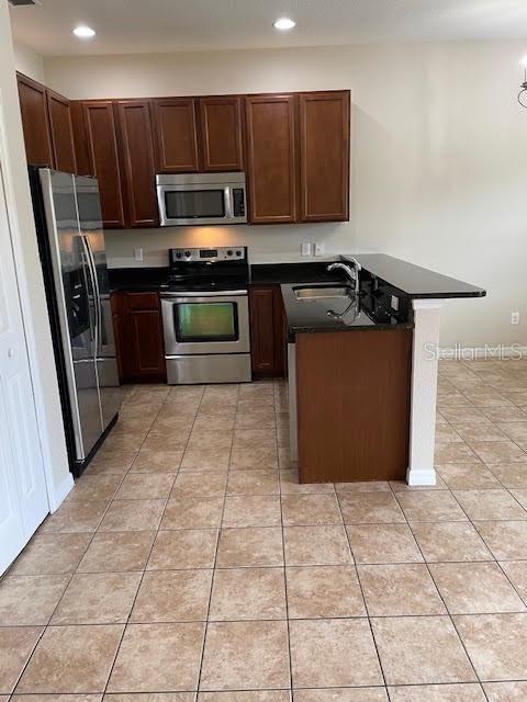 A kitchen features dark wood cabinets, stainless steel appliances, and a granite-topped breakfast bar — 3809 BLACK SPRUCE LANE, WINTER SPRINGS, FL