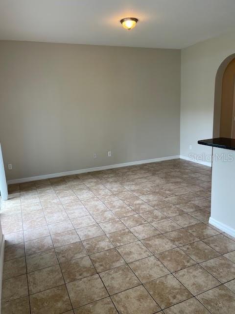 An empty room features tan tile flooring, light-colored walls, and a single ceiling light fixture — 3809 BLACK SPRUCE LANE, WINTER SPRINGS, FL