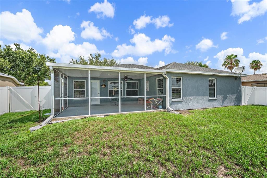 The exterior of a house features a screened-in back porch and a grassy backyard — 12017 LARSON LANE, PARRISH, FL