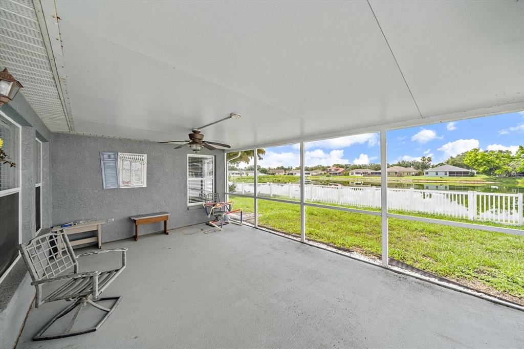 A screened-in patio features a concrete floor, a ceiling fan, and views of a pond — 12017 LARSON LANE, PARRISH, FL