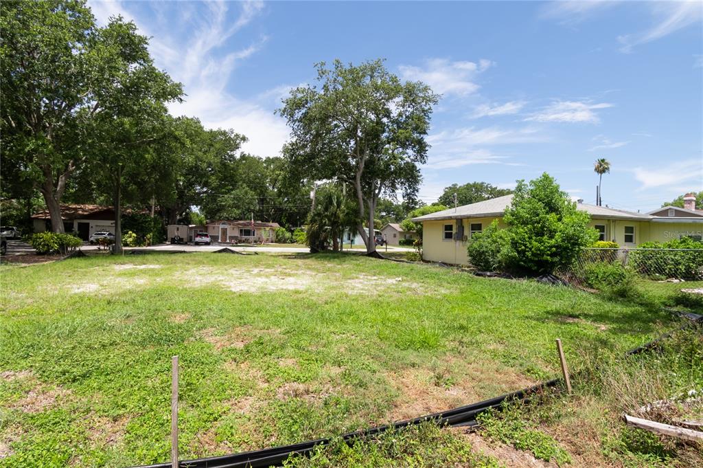 A vacant, grassy residential lot sits between neighboring houses under a blue sky — 658 15TH STREET NW, LARGO, FL