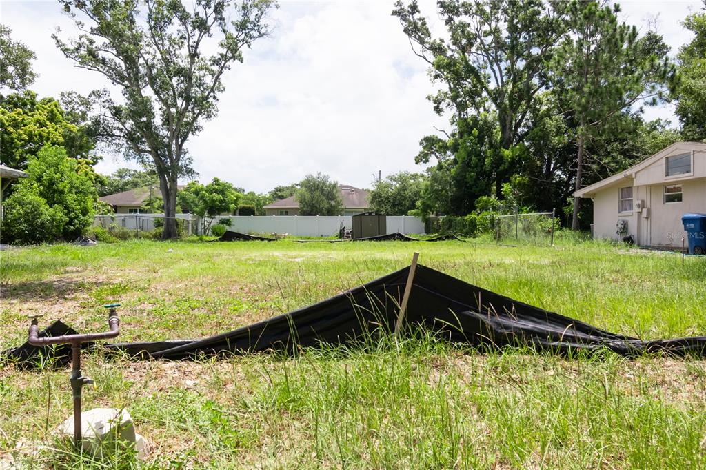 A vacant, grassy residential lot features silt fencing and a water spigot in the foreground — 658 15TH STREET NW, LARGO, FL