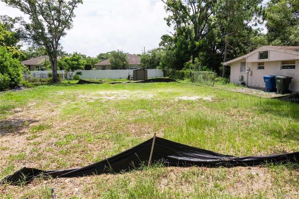 A vacant residential lot features a silt fence and an adjacent house with trash bins — 658 15TH STREET NW, LARGO, FL