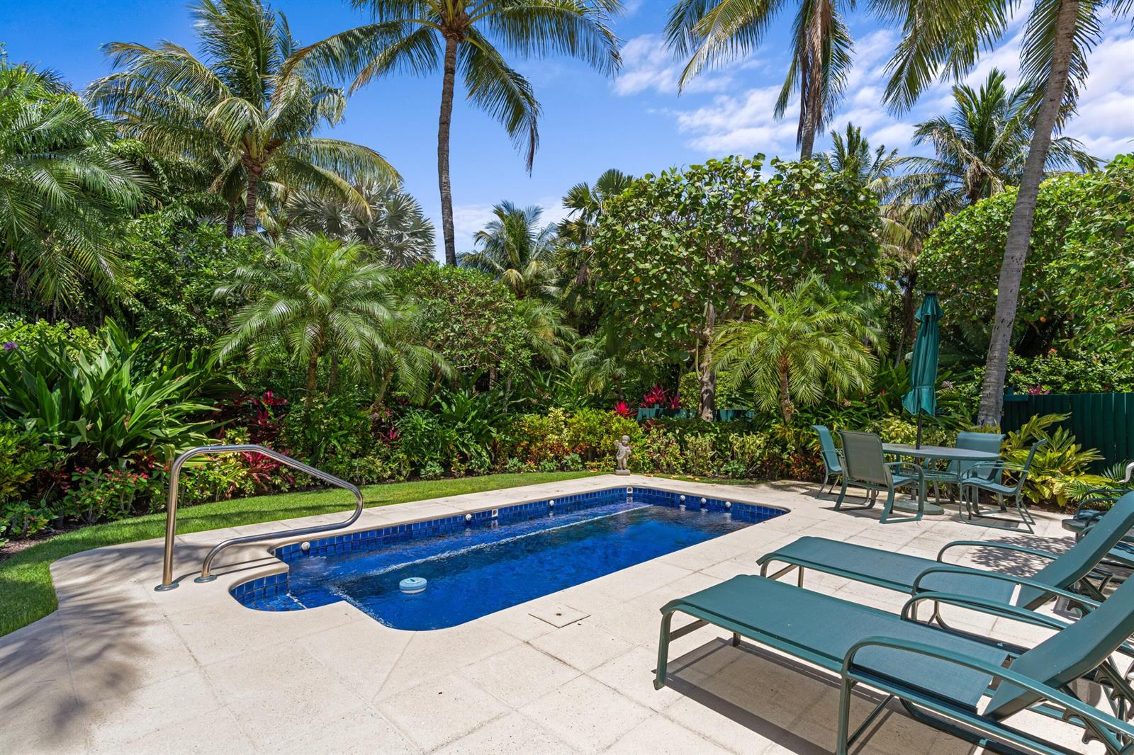 A rectangular swimming pool with a metal handrail sits on a patio with lounge chairs — 1554 N Ocean Way, Palm Beach FL 33480, PALM BEACH, FL