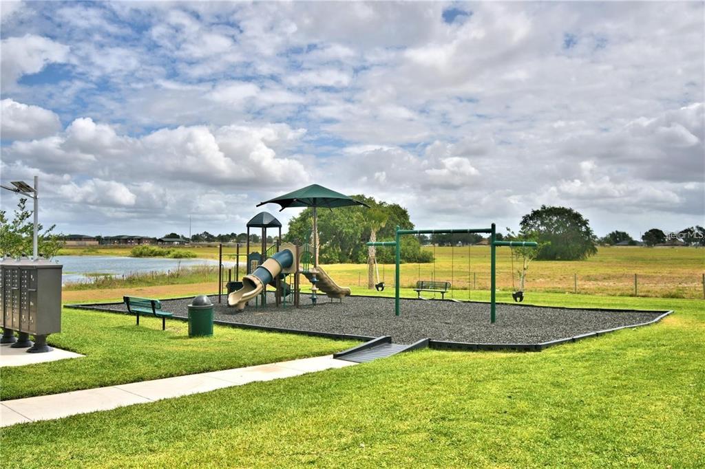 A playground with a slide, swings, and benches sits on a gravel lot near water — 2335 BRASSIE COURT, WINTER HAVEN, FL