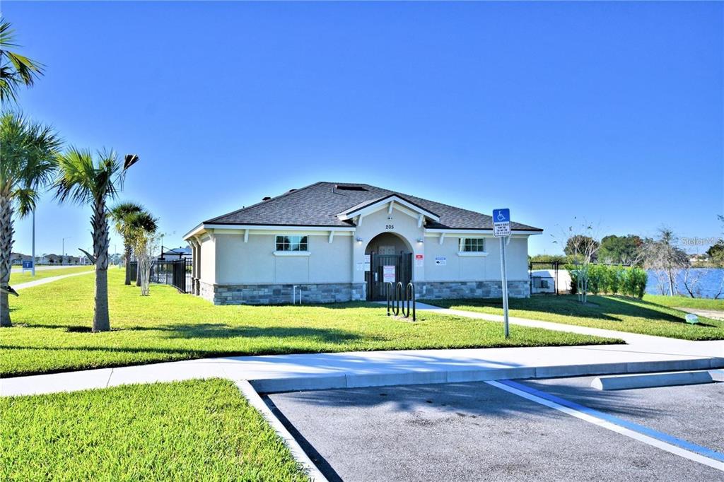 A single-story community building with a stone base, a gated entrance, and surrounding palm trees — 2335 BRASSIE COURT, WINTER HAVEN, FL