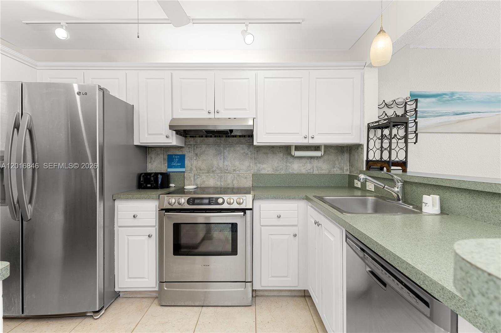 A kitchen features white cabinets, stainless steel appliances, and green countertops — 1391 S Ocean Blvd # 409, Pompano Beach FL 33062, POMPANO BEACH, FL