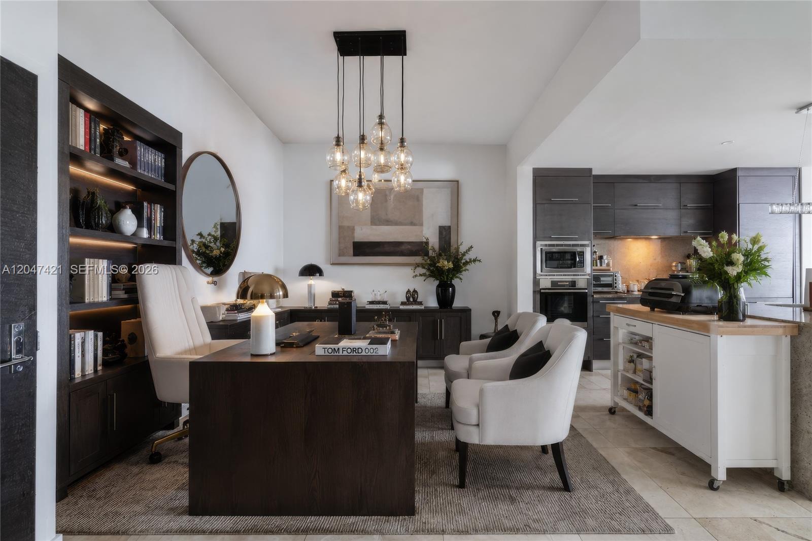 A modern home office features a dark wood desk, built-in shelving, and two white armchairs — 900 Biscayne Blvd # 4205, Miami FL 33132, MIAMI, FL