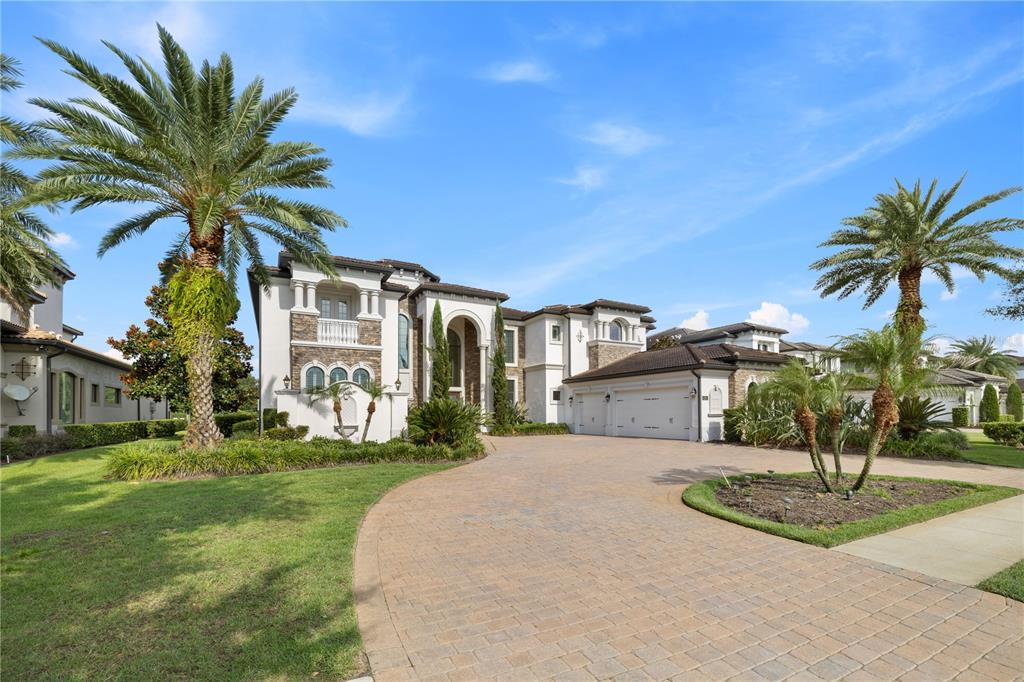 A large two-story house with a paved driveway, palm trees, and a three-car garage — 4201 ISABELLA CIRCLE, WINDERMERE, FL