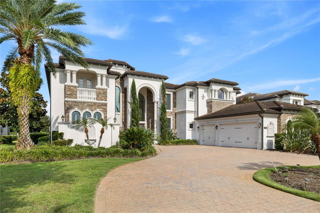 A large, two-story Mediterranean-style house with a stone facade, white stucco, and a paver driveway — 4201 ISABELLA CIRCLE, WINDERMERE, FL