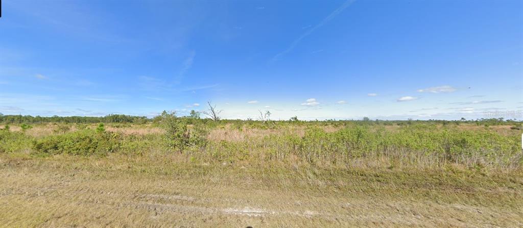 A wide, flat, undeveloped grassy field under a clear blue sky — 518 PORTULACA DRIVE, INDIAN LAKE ESTATES, FL