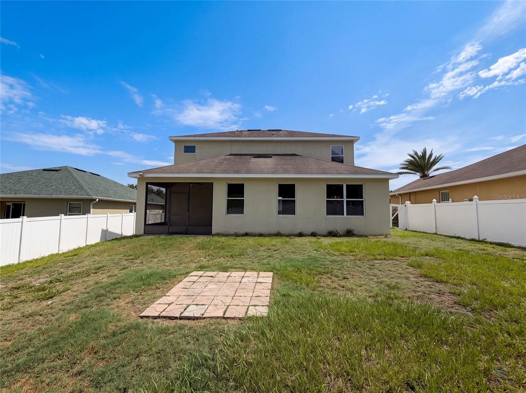 The rear exterior of a two-story house features a screened patio and a white fence — 881 HARING LANE, MOUNT DORA, FL
