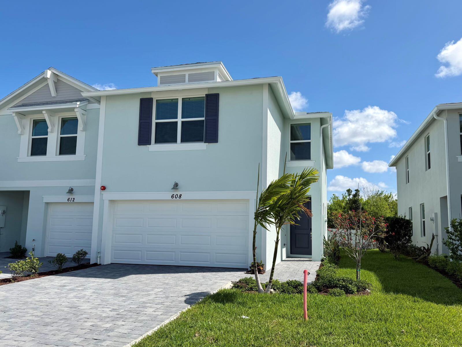 A row of light-colored townhouses features paved driveways, white garage doors, and green lawns — 608 Salisbury Circle, Fort Pierce FL 34982, FORT PIERCE, FL