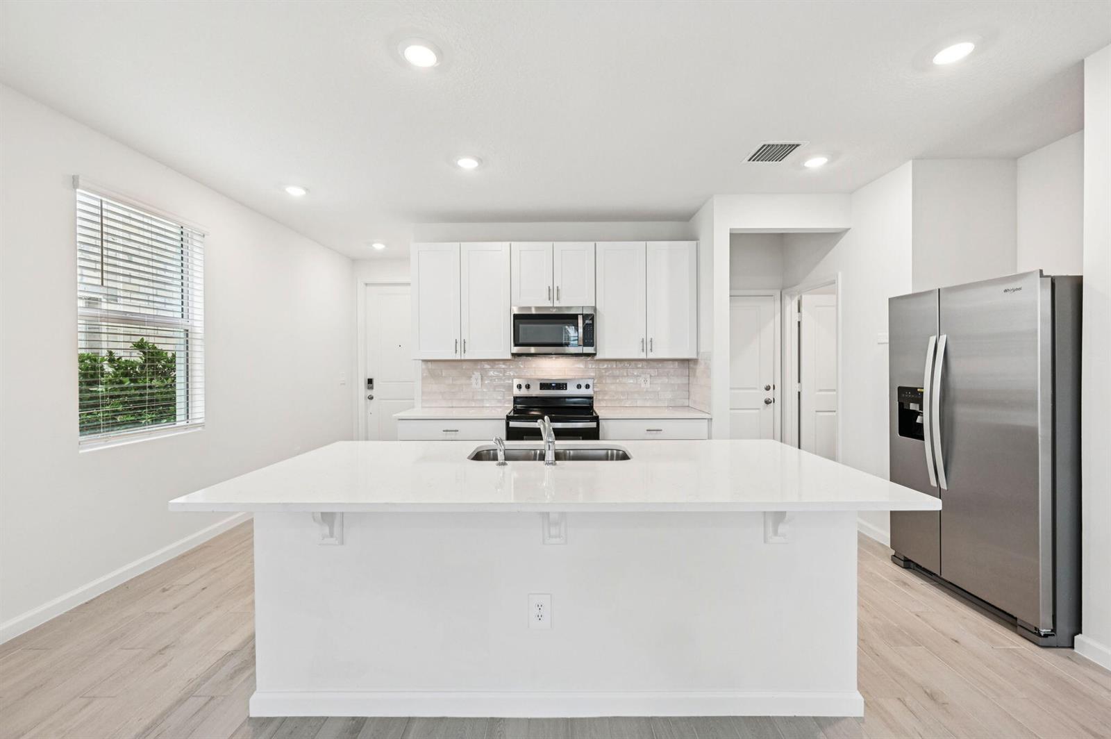 A light green two-story townhouse with a white garage door and a paved driveway — 608 Salisbury Circle, Fort Pierce FL 34982, FORT PIERCE, FL