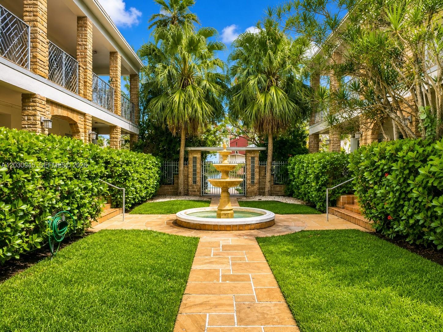 A stone fountain sits in the center of a courtyard between two brick apartment buildings — 2137 Calais Dr # 5, Miami Beach FL 33141, MIAMI BEACH, FL