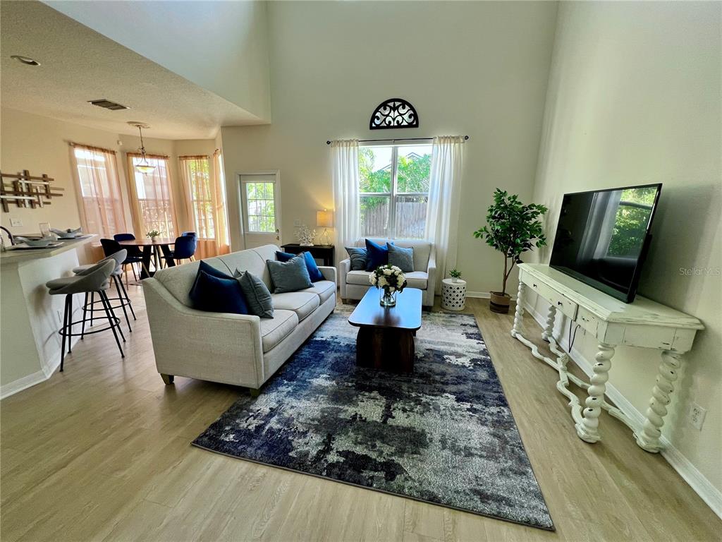 A living room with a high ceiling, a large area rug, and a white console table — 411 DURHAM SHORE COURT, APOLLO BEACH, FL