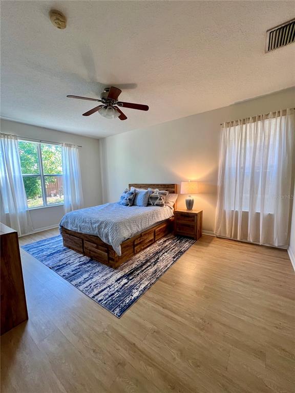 A bedroom features a wooden bed frame, a ceiling fan, and light wood flooring — 411 DURHAM SHORE COURT, APOLLO BEACH, FL