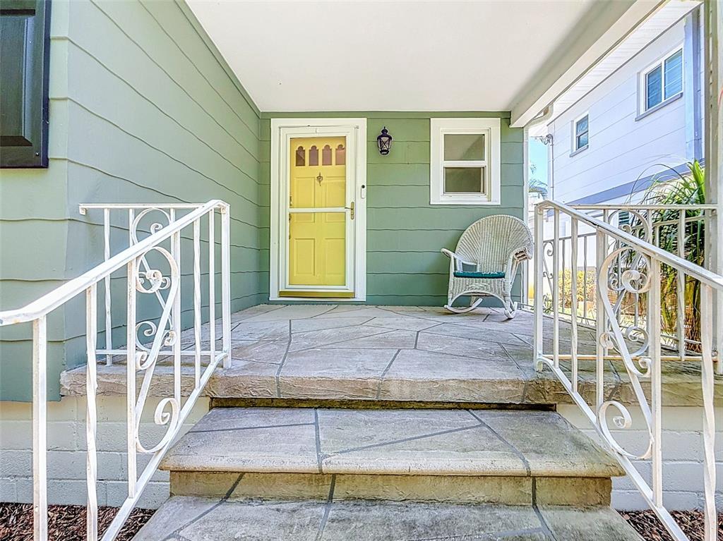 A front porch features a yellow door, a white wicker chair, and stone steps — 182 29TH AVENUE N, ST PETERSBURG, FL