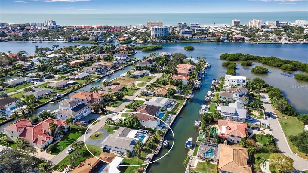 An aerial view shows a waterfront house with a pool and dock in a neighborhood — 1649 STANFORD LANE, SARASOTA, FL