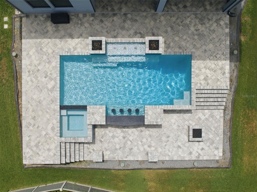 An aerial view of a rectangular swimming pool with an attached spa and stone patio — 4335 ORTONA LANE, WESLEY CHAPEL, FL