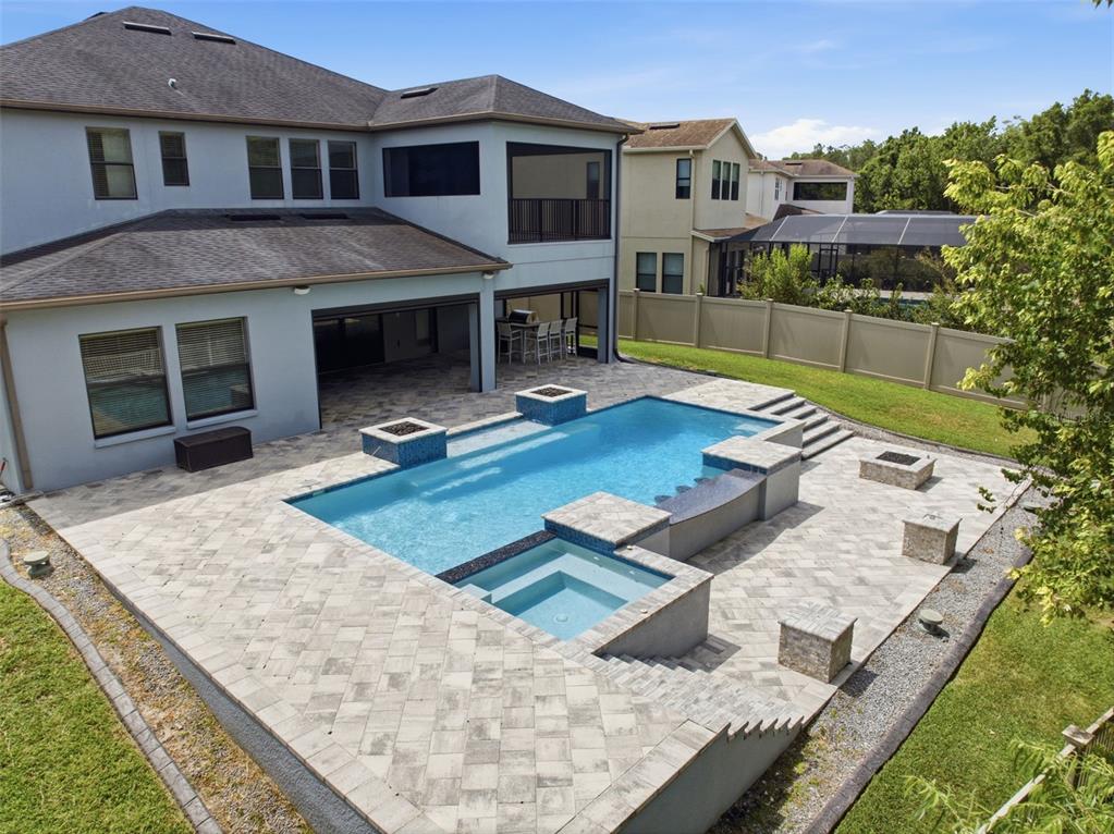 An elevated view of a backyard featuring a swimming pool, spa, and stone paver patio — 4335 ORTONA LANE, WESLEY CHAPEL, FL