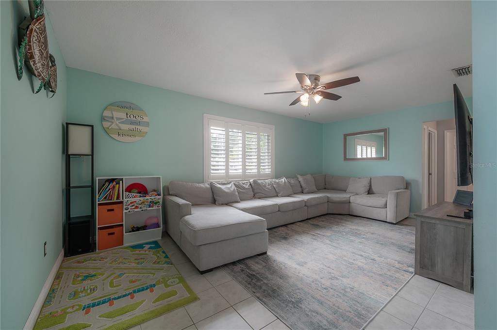 A living room features light blue walls, a large sectional sofa, and a patterned rug — 5937 13TH AVENUE N, ST PETERSBURG, FL
