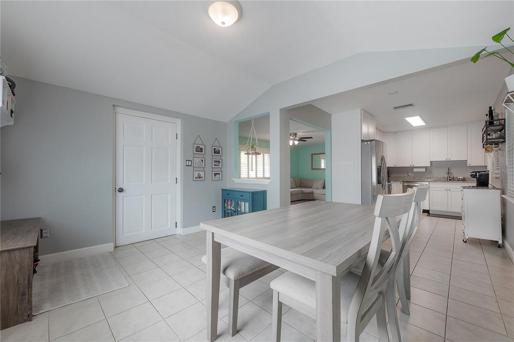 A dining area with light wood furniture, tile flooring, and an open view into the kitchen — 5937 13TH AVENUE N, ST PETERSBURG, FL