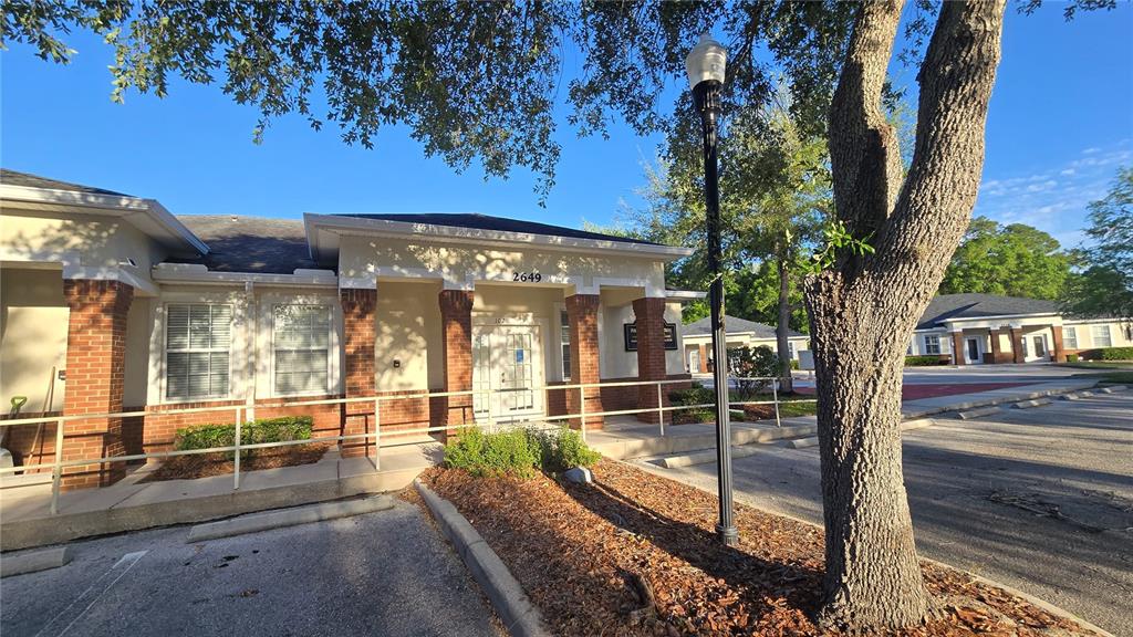 A single-story commercial building with brick columns, a white door, and a parking lot — 2649 WINDGUARD CIRCLE UNIT 102, WESLEY CHAPEL, FL