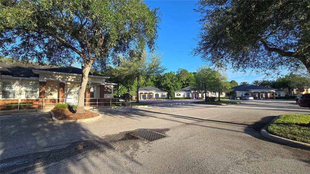 An exterior view of a commercial office complex with parking and mature trees — 2649 WINDGUARD CIRCLE UNIT 102, WESLEY CHAPEL, FL