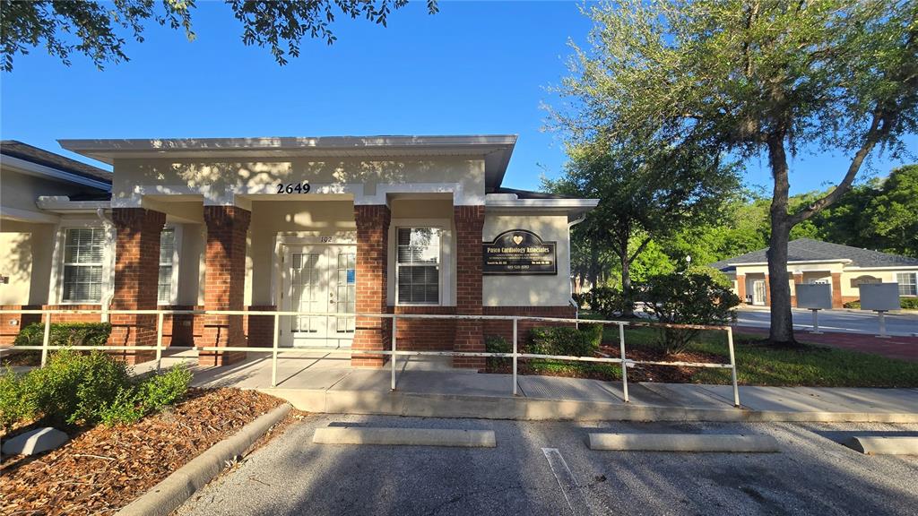 A single-story commercial building with a brick facade and a white-railed entrance ramp — 2649 WINDGUARD CIRCLE UNIT 102, WESLEY CHAPEL, FL