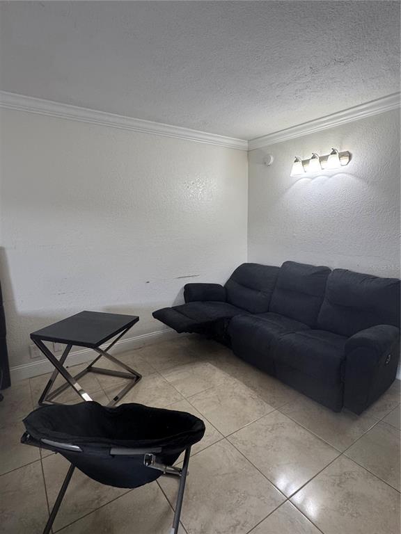 A living room features a dark reclining sofa, a small side table, and tiled flooring — 43420 HIGHWAY 27 UNIT 312, DAVENPORT, FL