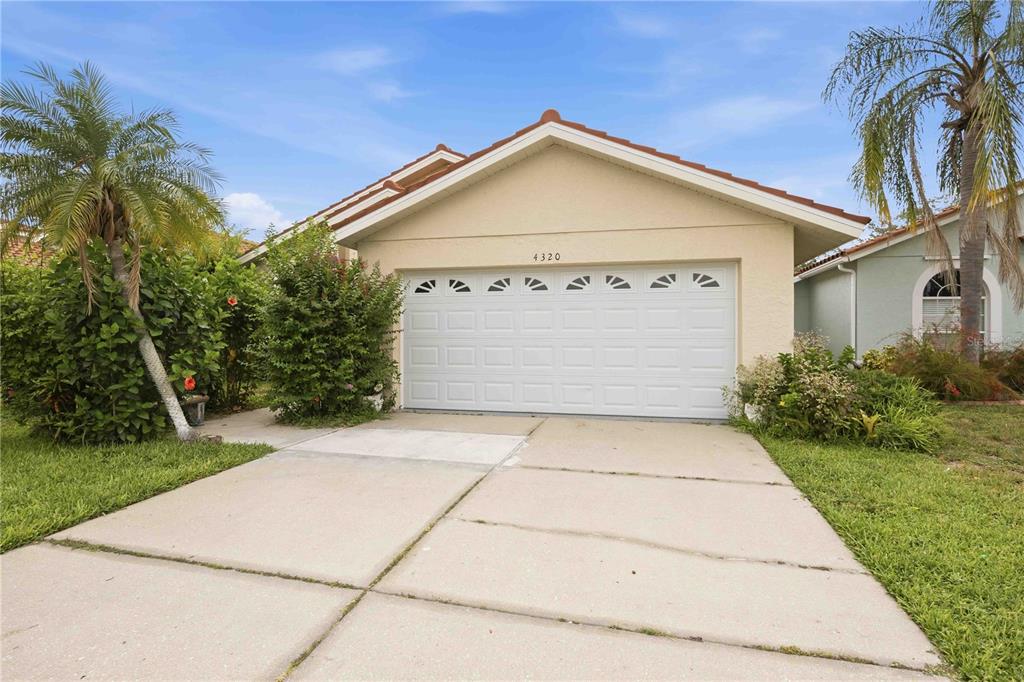 A single-story house with a white garage door, palm trees, and a landscaped front yard — 4320 MARCOTT CIRCLE, SARASOTA, FL