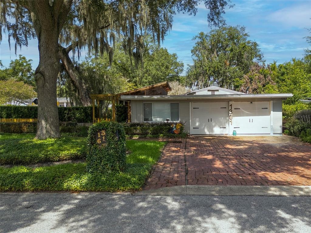 A single-story house with a brick driveway, a two-car garage, and a large oak tree — 1361 AUDUBON ROAD, MAITLAND, FL