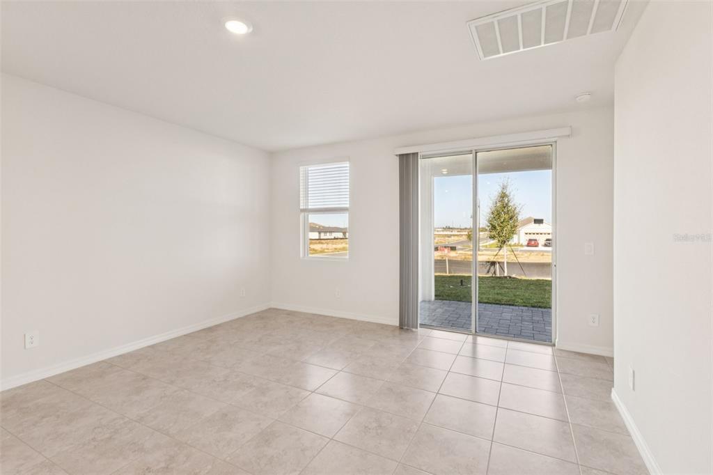 A bright room with light tile flooring, a single window, and sliding glass patio doors — 879 SUNSHOWER DRIVE, LADY LAKE, FL