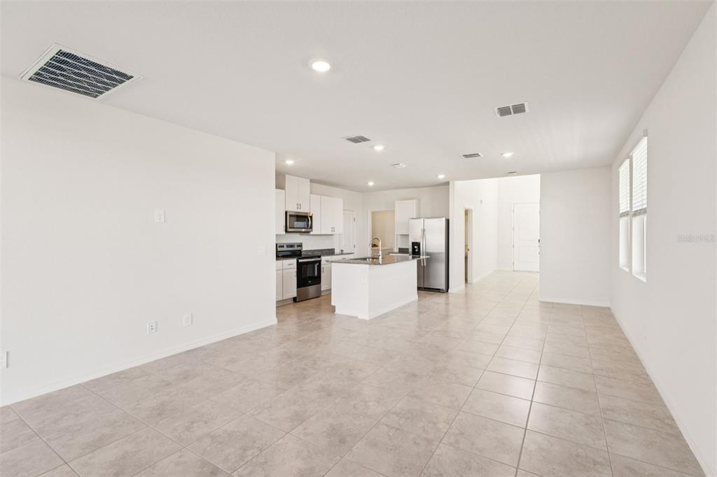 An open-concept kitchen and living area features white cabinetry, stainless steel appliances, and tile flooring — 879 SUNSHOWER DRIVE, LADY LAKE, FL