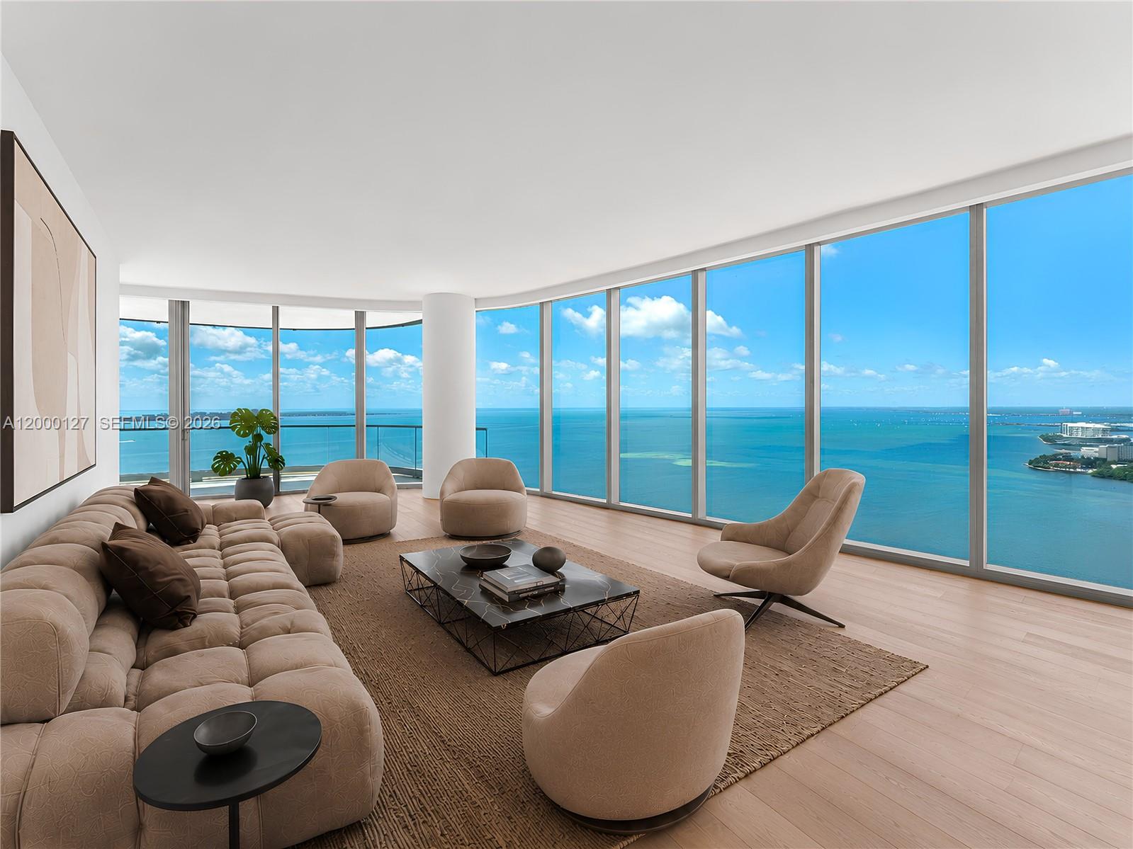 A modern living room features a large sectional sofa, floor-to-ceiling windows, and ocean views — 175 SE 25th Road # 3602, Miami FL 33129, MIAMI, FL