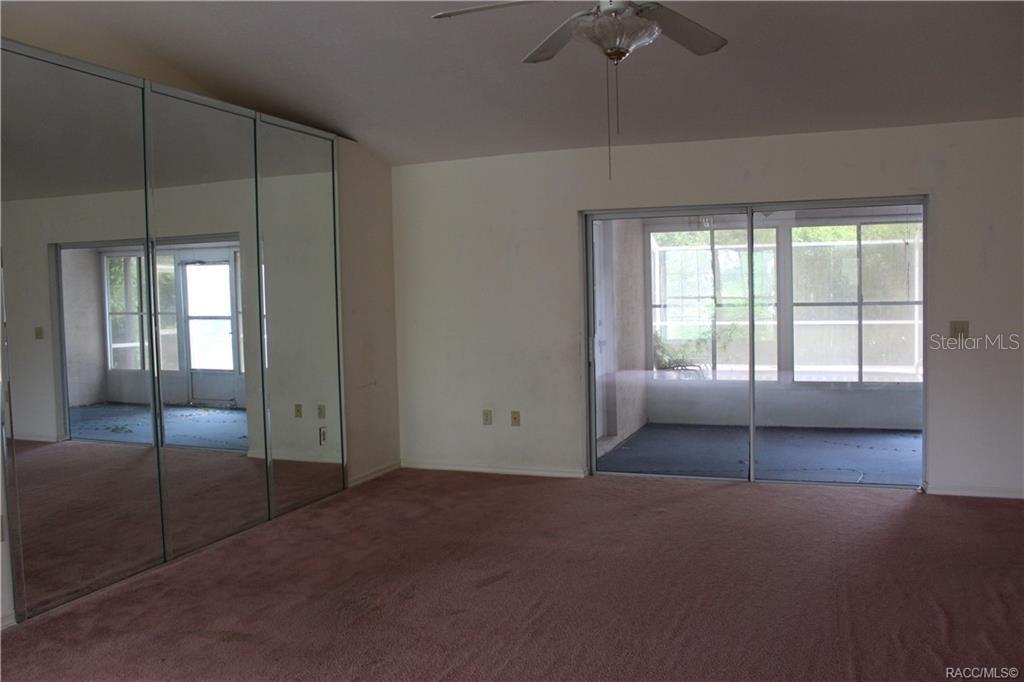 A room with pink carpet, mirrored closet doors, a ceiling fan, and sliding glass doors — 742 W SUNSET STRIP DRIVE, BEVERLY HILLS, FL
