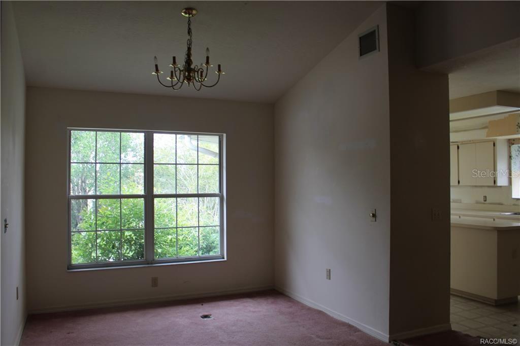 A dining area with pink carpet, a chandelier, and a large window overlooking trees — 742 W SUNSET STRIP DRIVE, BEVERLY HILLS, FL