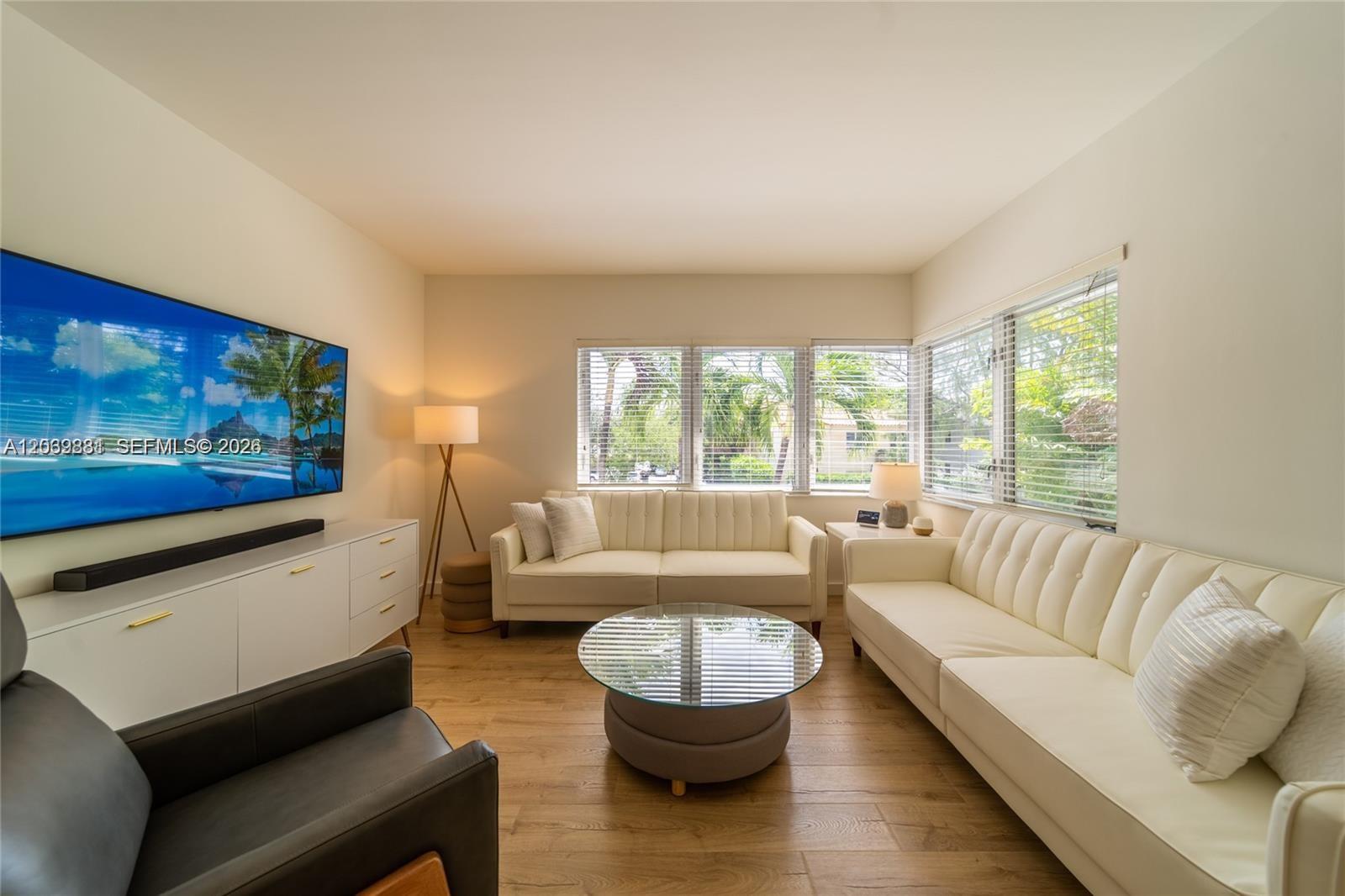 A living room features two white sofas, a glass coffee table, and a wall-mounted television — 1616 Euclid Ave # 2, Miami Beach FL 33139, MIAMI BEACH, FL