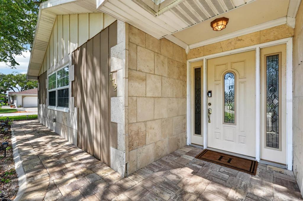 A paved walkway leads to the front entrance of a house with stone-tiled walls — 772 N BEACH STREET, ORMOND BEACH, FL