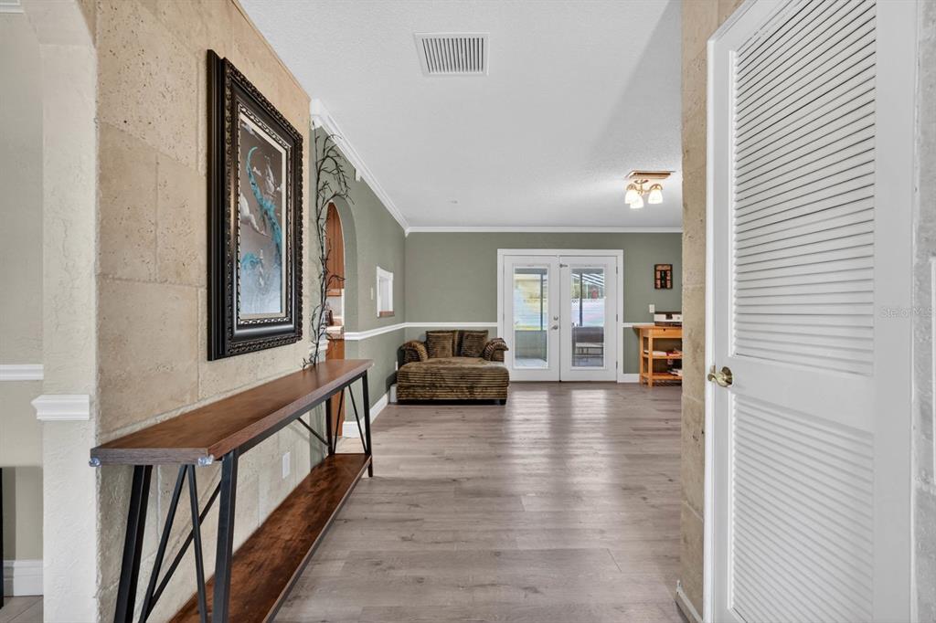 A hallway with wood-look flooring leads into a living area with a couch and doors — 772 N BEACH STREET, ORMOND BEACH, FL