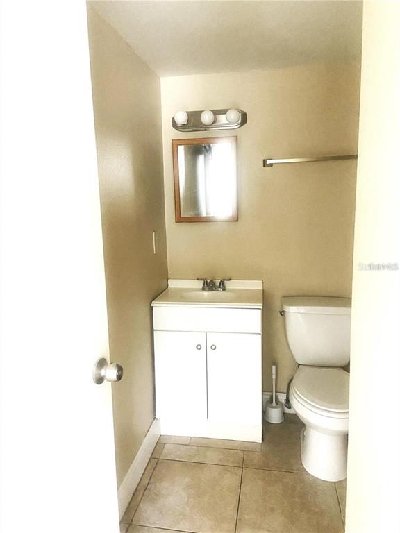 A small bathroom features a white vanity, a wall-mounted mirror, and a white toilet — 4133 DOLPHIN DRIVE UNIT 4133, TAMPA, FL
