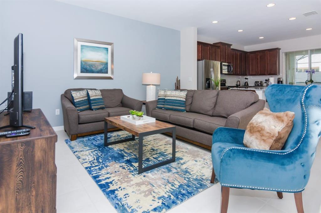 A living room features a blue area rug, two gray sofas, and a blue armchair — 1534 CAREY PALM CIRCLE, KISSIMMEE, FL
